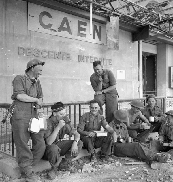 Infantrymen of The Stormont, Dundas and Glengarry Highlanders  eating lunch outside the railroad station, Vaucelles, France,  20 July 1944.