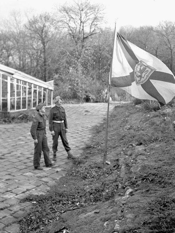 Regimental Sergeant-Major J.L. McNeil and Sergeant K.P. Grant raising the regimental flag of The North Nova Scotia Highlanders for the first time in Germany. Wyler, Germany, 19 November 1944.