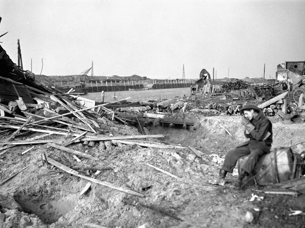 Private J. Gustilov of  the 1st Battalion, The Canadian Scottish Regiment, examining the wreckage of fishing vessels, Breskens, Netherlands, 28 October 1944.