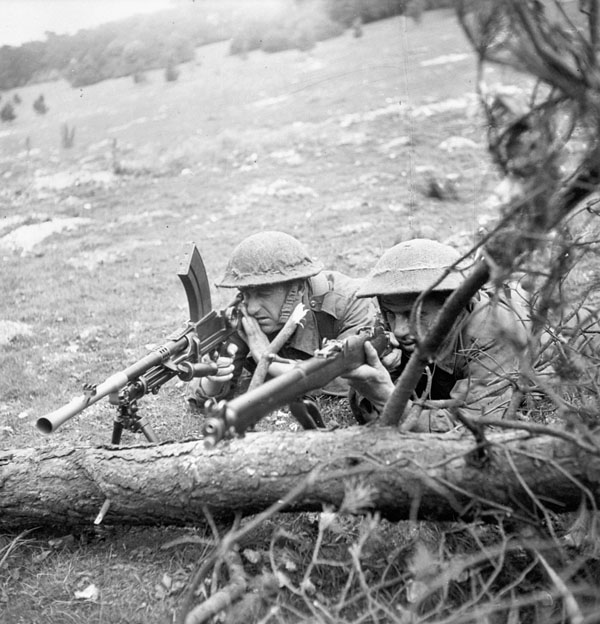 Unidentified infantrymen of The Highland Light Infantry of Canada, who are armed with a Bren light machine gun and a sniper rifle, taking part in a training exercise, England, 11 June 1943.