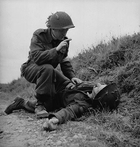 H/Captain Robert Seaborn, Chaplain of the 1st Battalion, The Canadian Scottish Regiment, giving absolution to an unidentified soldier of the 3rd Canadian Infantry Division near Caen, France, 15 July 1944.