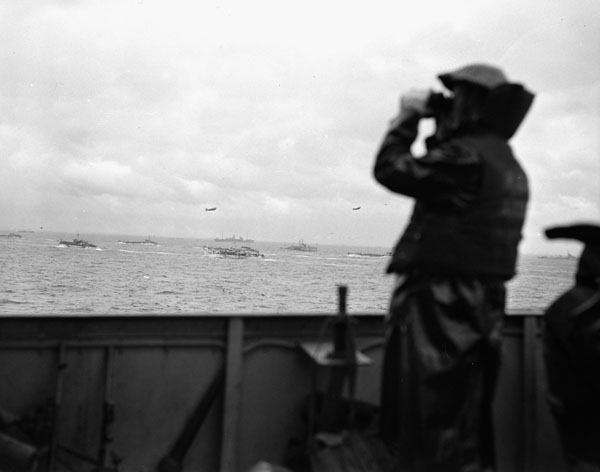 Lookout on the flagdeck of H.M.C.S. PRINCE DAVID watching assault craft  heading ashore to the Normandy beachhead, France, 6 June 1944.