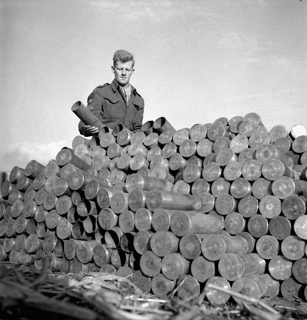 Sergeant E.F. Offord, 4th Field Regiment, Royal Canadian Artillery (R.C.A.), piling empty shell cartridges, Ossendrecht, Netherlands, 23 October 1944.