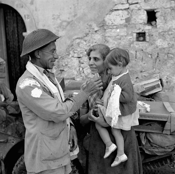 Trooper Ralph Catherall of The Calgary Regiment giving food to an Italian child, Volturara, Italy, 3 October 1943.