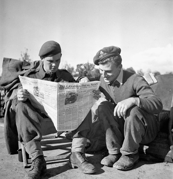 Sergeant M.T. Stokes and Gunner A.E. Norton, both of the 4th Field Regiment, Royal Canadian Artillery (R.C.A.), reading an issue of Canadian Press News near Antwerp, Belgium, 2 October 1944.