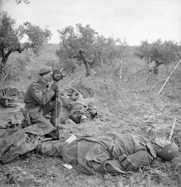 Sergeant George A. Game of the Canadian Army Film and Photo Unit operating his camera near San Leonardo di Ortona, Italy, 10 December 1943.