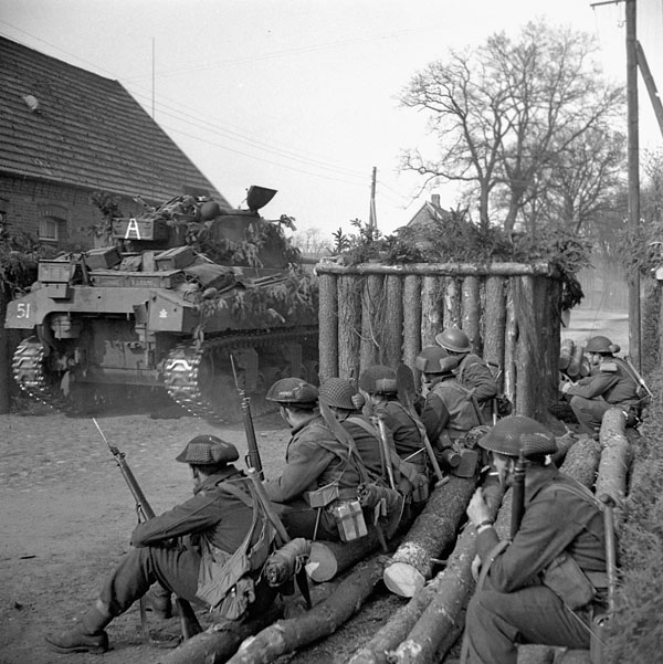Infantrymen of the Lincoln and Welland Regiment and a Sherman tank of the 4th Canadian Armoured Division awaiting orders to go through a roadblock, Wertle, Germany, 11 April 1945.