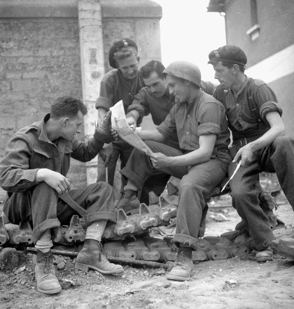 Personnel of a Canadian armoured regiment, possibly the Canadian Grenadier Guards, reading the first issue of the Maple Leaf newspaper between Fleury-sur-Orne and Ifs, France, 28 July 1944.