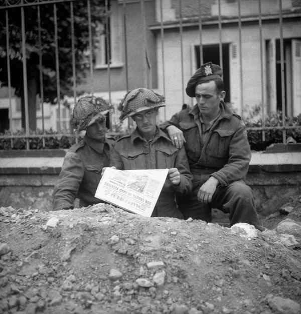 Personnel of the Calgary Highlanders reading the first issue of the Maple Leaf newspaper , Caen, France, 28 July 1944.