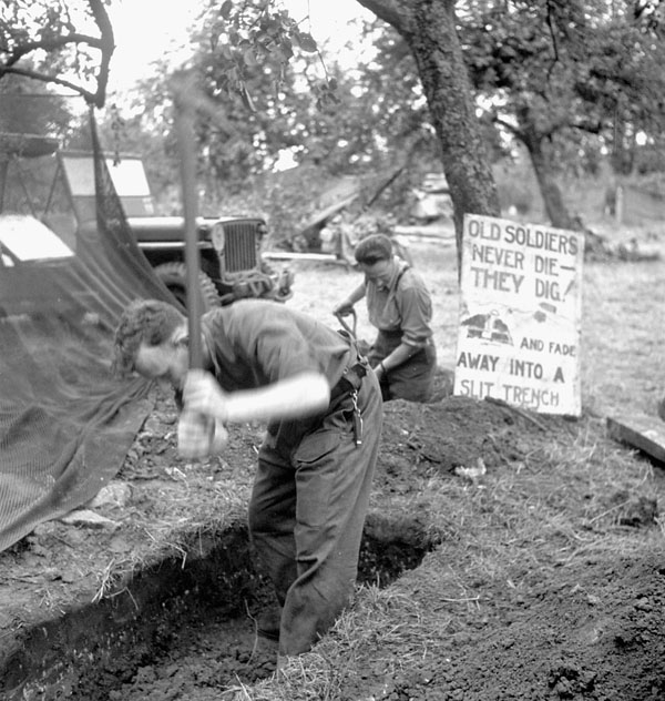 Signalman Rusty Forsythe and Captain R.W. Armstrong digging slit trenches during Operation SPRING south of Ifs, France, 25 July 1944.