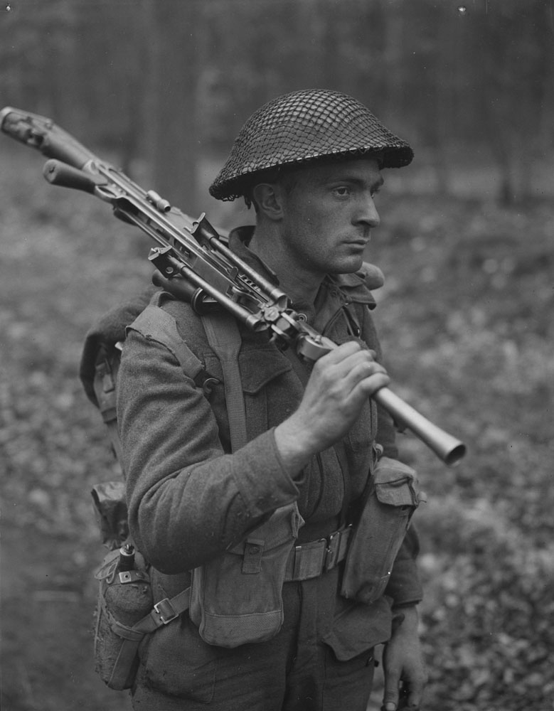 Private H.E. Goddard of The Perth Regiment, carrying a Bren gun while advancing through a forest north of Arnhem, Netherlands.
