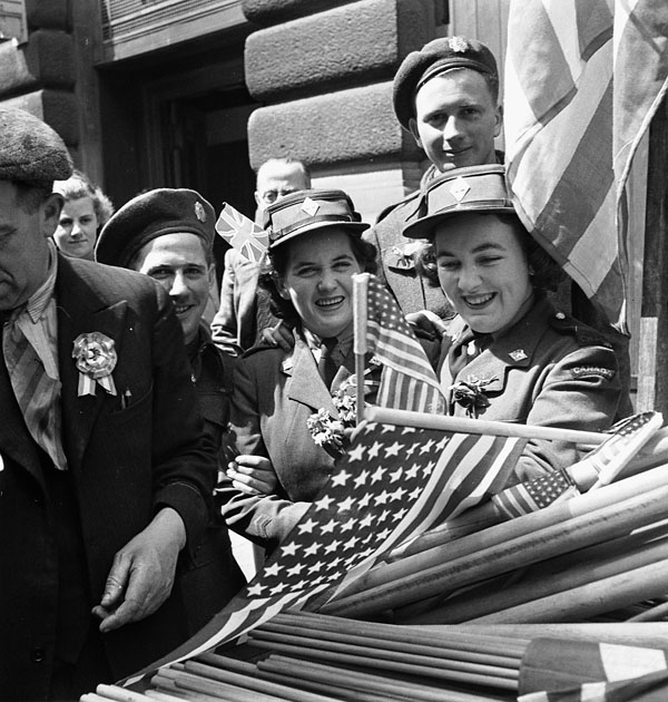 Canadian soldiers and members of the Canadian Women's Army Corps (C.W.A.C.) buying flags to wave in V-E Day celebrations, London, England, 8 May 1945.