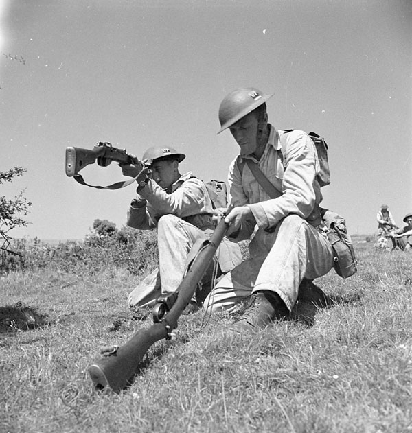 Gunners Elgin Buckland and F.J. Campbell of the 5th Medium Regiment, Royal Canadian Artillery (R.C.A.), cleaning the barrels of their Lee-Enfield rifles, England, 17 July 1943.
