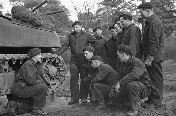Tank crews of the Canadian Grenadier Guards are briefed on maintenance of the tracks of a Ram tank, England, 24 January 1943.