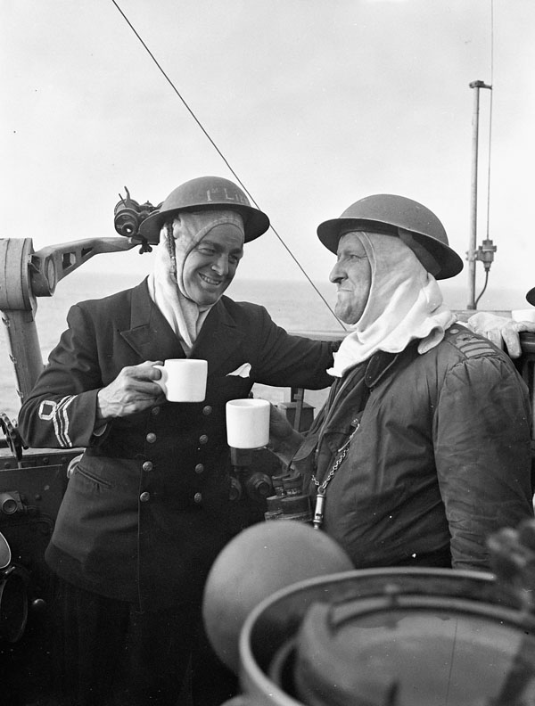 Lieutenant-Commander C.R. “Tony” Coughlin (left), First Lieutenant, and Commander James C. Hibbard (right), Commanding Officer, on the bridge of H.M.C.S. IROQUOIS after a five-hour battle in which eight German ships were destroyed or damaged while attempting to escape from St. Nazaire, France, 21 August 1944.