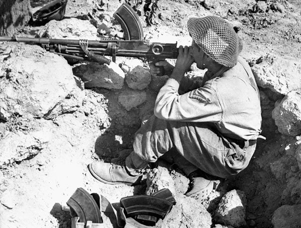 Lance-Corporal J.A. Weston, West Nova Scotia Regiment, aiming his Bren gun across the Foglia River during the advance on the Gothic Line near Montelabbate, Italy, ca. 30 August 1944.