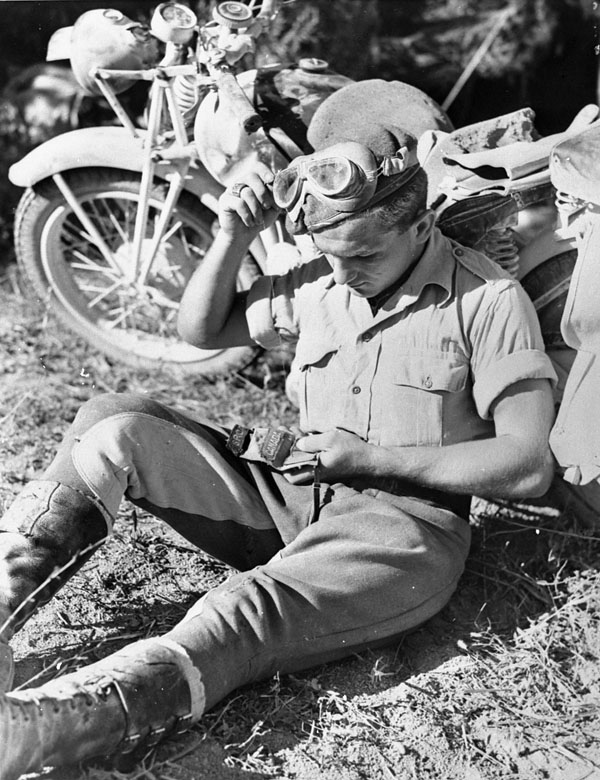 An unidentified Canadian despatch rider holding regimental shoulder flashes during the assault on the Gothic Line, Italy, ca. 26 August - 3 September 1944.