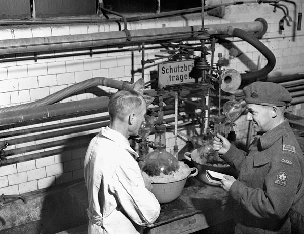 Dr. Paul Larose (right) of the National Research Council of Canada talking with a German scientist in the chemical laboratory of a metal alloy plant, Heddesheim, Germany, ca. 4 - 10 September 1945.