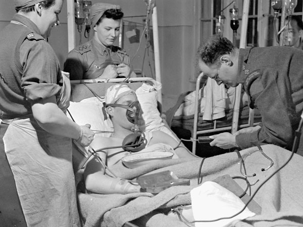 Personnel of No.5 Field Dressing Station and Surgical Unit, Royal Canadian Army Medical Corps (R.C.A.M.C.),  performing an aspiration to draw blood out of the cavity surrounding the lungs of a patient with a chest and abdomen injury. The location of the Unit is on the road between Cleve and Udem, Germany, 2 March 1945.