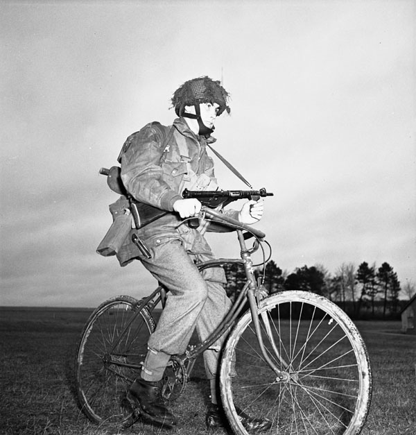 Private Tom J. Phelan, 1st Canadian Parachute Battalion, who was wounded on 16 June 1944 at Le Mesnil, rides his airborne folding bicycle at the battalion's reinforcement camp, England, 1944.
