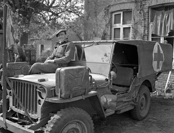Private F.J. Dunn resting on his ambulance jeep while evacuating casualties south of Bad Zwischenahn, Germany, 29 April 1945.